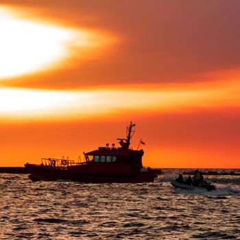 Pilot ship and the dinghy on speed during hot sunset, Latvia