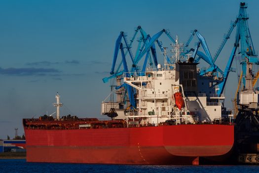 Red cargo ship loading in the port of Riga, Europe