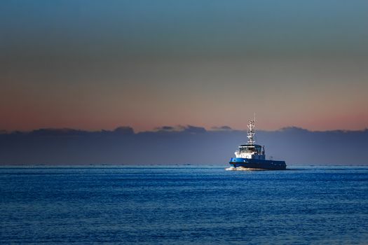 Blue small tug ship sailing from the Baltic sea in the morning