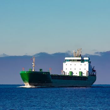 Green cargo ship moving in still water of Baltic sea