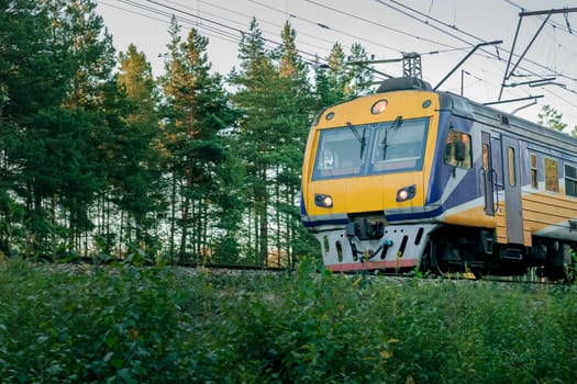 Passenger electric train moving through forest in Riga