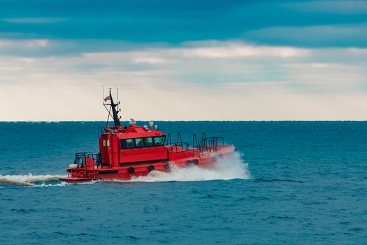 Red pilot ship sailing in still Baltic sea water