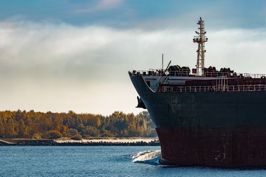 Black cargo ship's bow entering Riga, Europe