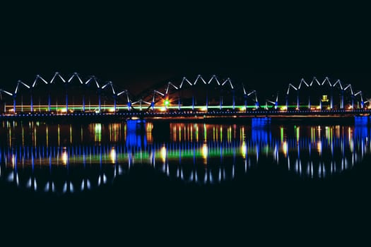 Illuminated railroad bridge in night city, Latvia. Riga bridge