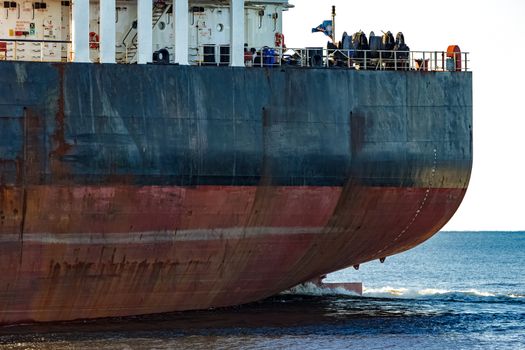 Black cargo ship's stern in still water close up. Riga, Europe