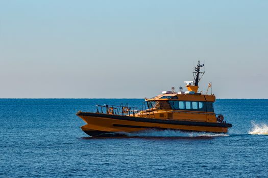 Yellow pilot ship moving at speed from the Baltic sea