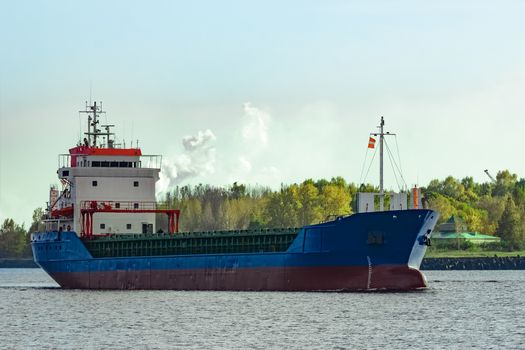 Blue cargo ship leaving the port of Riga at sunny day