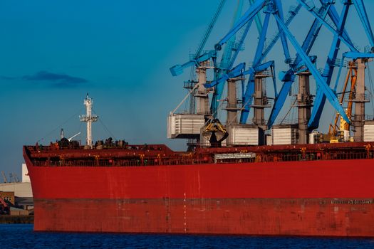 Red cargo ship loading in the port of Riga, Europe