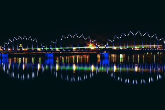 Illuminated railroad bridge in night city, Latvia. Riga bridge