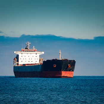 Black cargo ship moving in still Baltic sea water. Riga, Europe