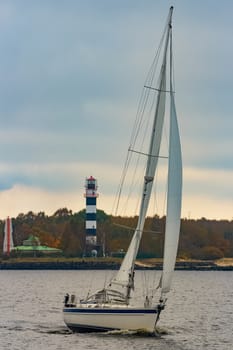 White sailboat traveling past the lighthouse in Riga