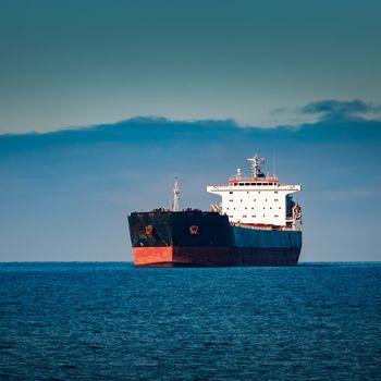 Black cargo ship moving in still Baltic sea water. Riga, Europe