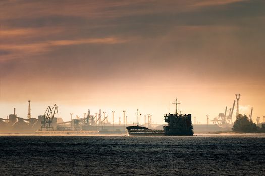 Cargo ship silhouette entering a port of Riga at the morning