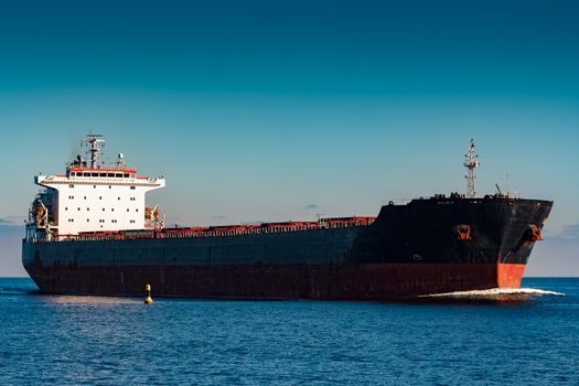 Black cargo ship moving in still Baltic sea water. Riga, Europe