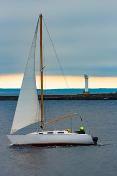 White sailboat traveling past the lighthouse in Riga