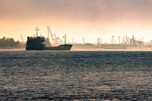 Cargo ship silhouette entering a port of Riga at the morning