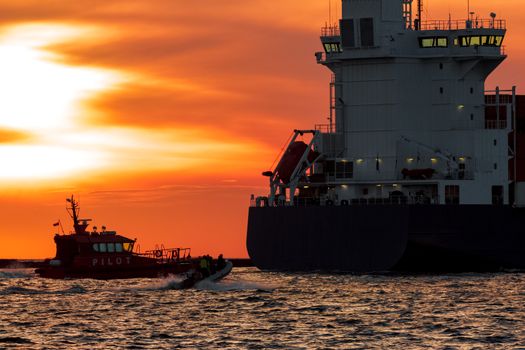 Pilot ship catches big container ship during hot sunset, Latvia