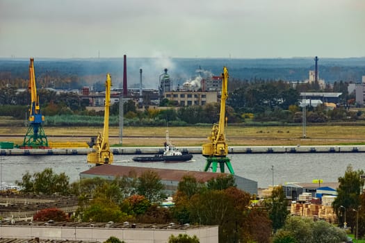 Tug ship moving past the cargo port at Riga city