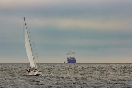 White sailboat traveling in Baltic sea in cloudy day