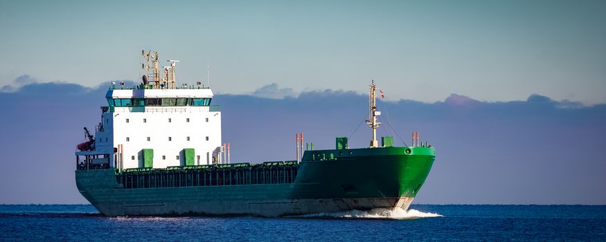 Green cargo ship moving in still water of Baltic sea