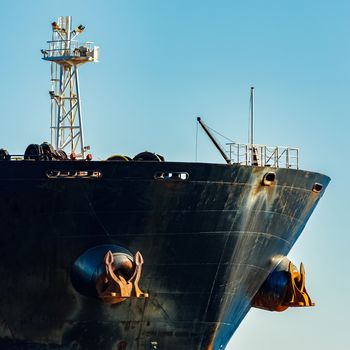 Black cargo ship's bow in still water. Riga, Europe