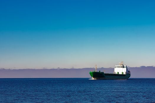 Green cargo ship moving in still water of Baltic sea
