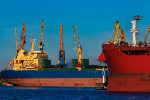 Red and blue cargo ship loading in the port of Riga