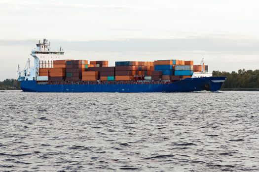 Blue container ship moving to Baltic sea. Riga, Latvia