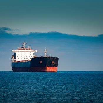 Black cargo ship moving in still Baltic sea water. Riga, Europe