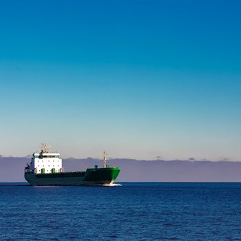 Green cargo ship moving in still water of Baltic sea