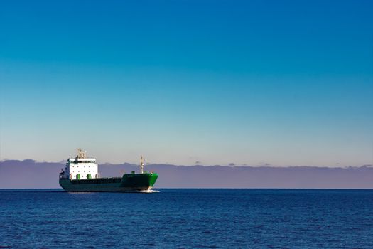 Green cargo ship moving in still water of Baltic sea