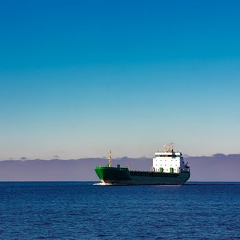 Green cargo ship moving in still water of Baltic sea