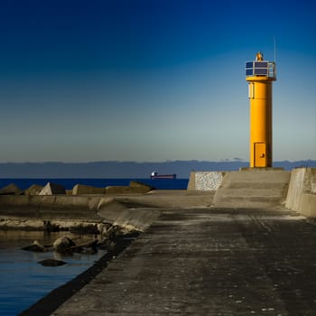 Yellow lighthouse on breakwater dam in Riga, Europe