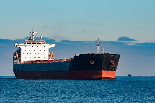 Black cargo ship moving in still Baltic sea water. Riga, Europe