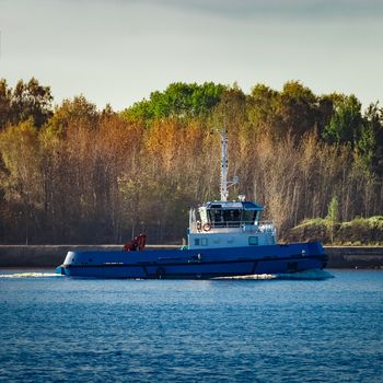 Blue small tug ship leaving Riga and entering the Baltic sea