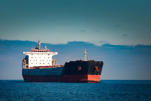 Black cargo ship moving in still Baltic sea water. Riga, Europe