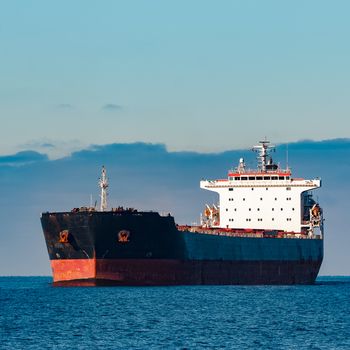 Black cargo ship moving in still Baltic sea water. Riga, Europe