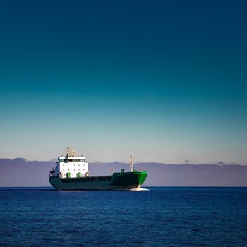 Green cargo ship moving in still water of Baltic sea