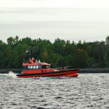 Orange pilot ship sailing on the Daugava river