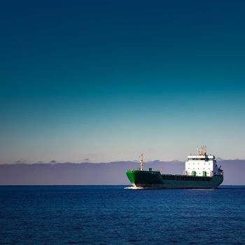 Green cargo ship moving in still water of Baltic sea