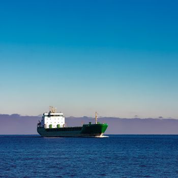 Green cargo ship moving in still water of Baltic sea