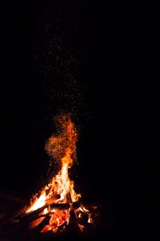 Campfire with flying sparks isolated on black background