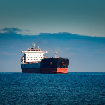 Black cargo ship moving in still Baltic sea water. Riga, Europe