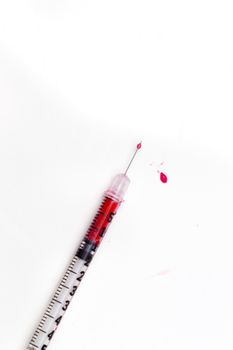 Blood-filled syringe on white background