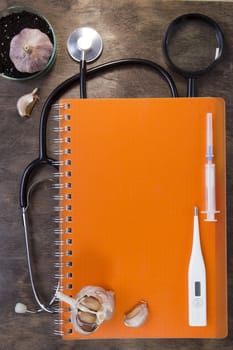 Medical instruments and orange notebook on a wooden background