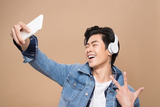 Portrait of a young asian handsome man with headphones smiling and listening to music
