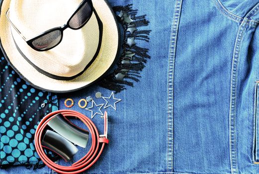 Top view of summer accessories for modern woman on her vacation stylish sunglasses Belt earring glasses Scarf, and striped beach  on denim jean background