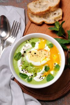 Pea puree soup with poached egg, sour cream, mint leaves seasoned with spices.