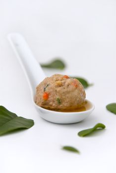 Pork meatball in kafir lime leaf broth served on a small white spoon