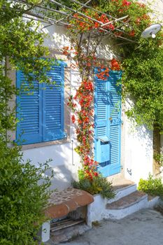 Typical Mediterranean house with white walls and blue fixtures. Boungaville flowers frame the windows.